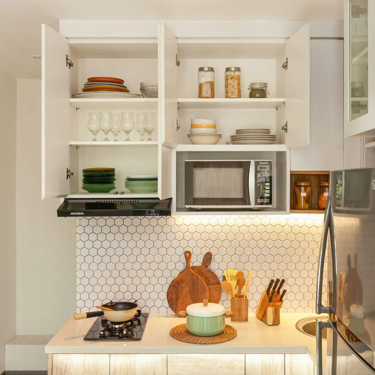 prendre - A clean, minimalist kitchen setting with glass jars containing dried herbal powders, a wooden spoon, a cup of herba