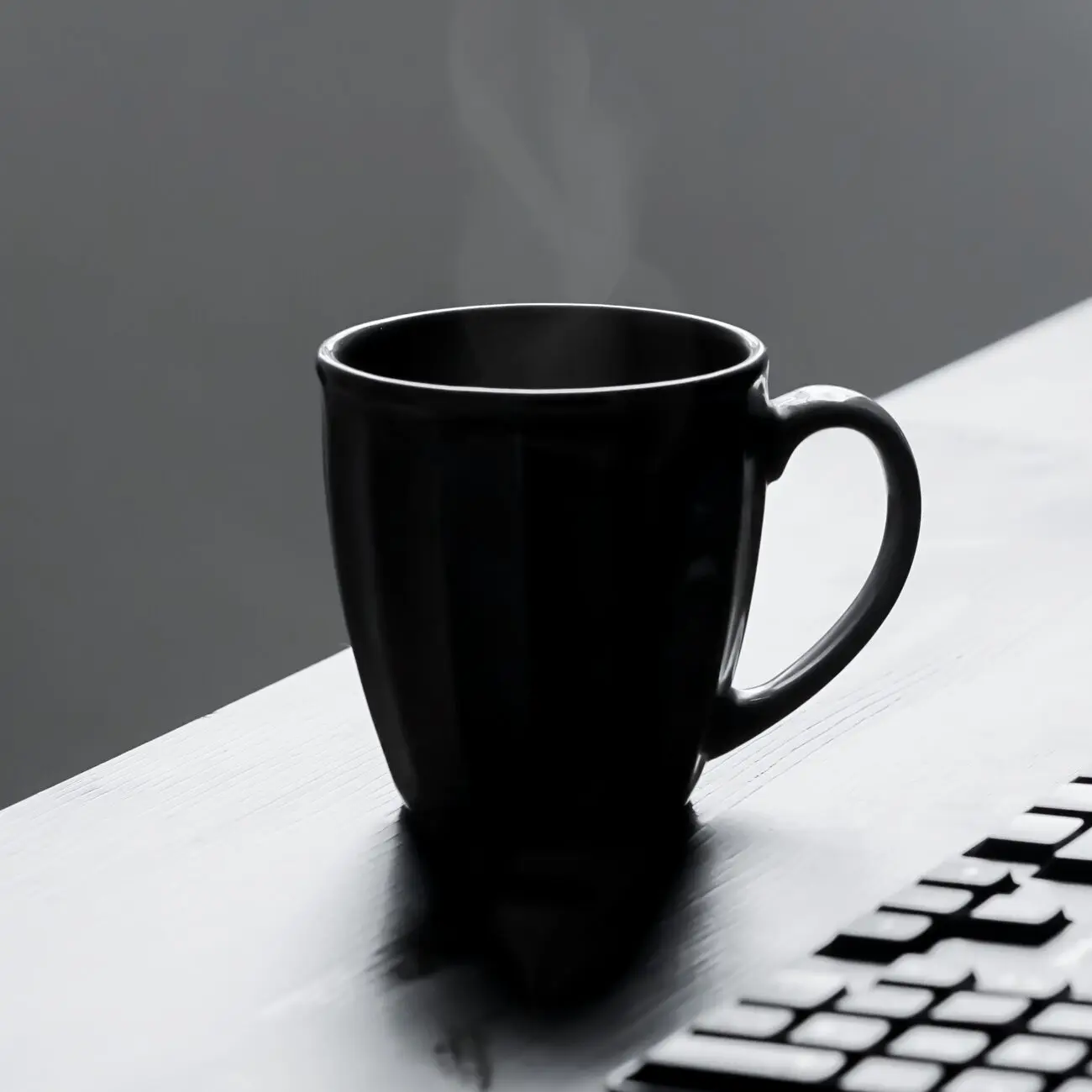 A steaming hot mug placed on a desk, perfect for a minimalist workplace setting.